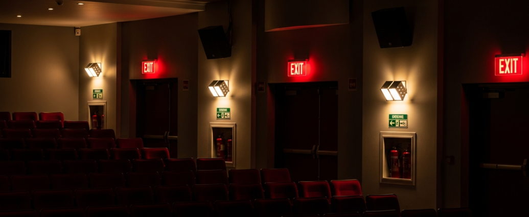 Theater auditorium showing emergency lighting systems and exit signs for fire safety compliance