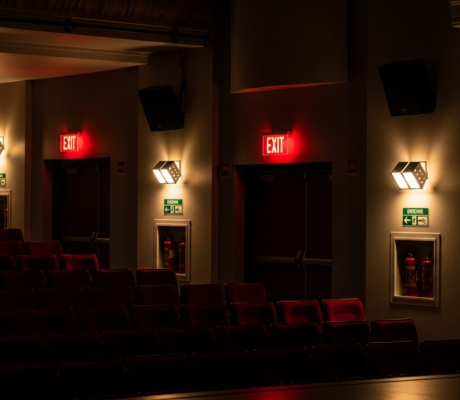 Theater auditorium showing emergency lighting systems and exit signs for fire safety compliance