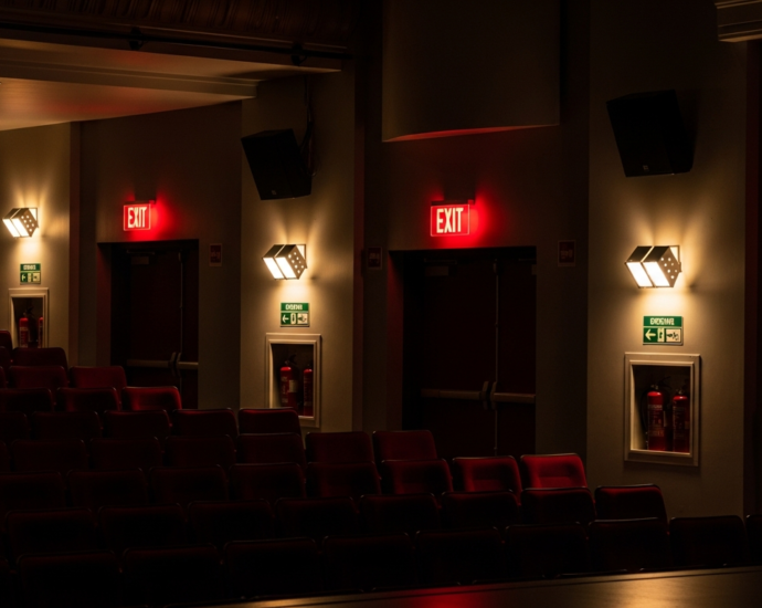 Theater auditorium showing emergency lighting systems and exit signs for fire safety compliance